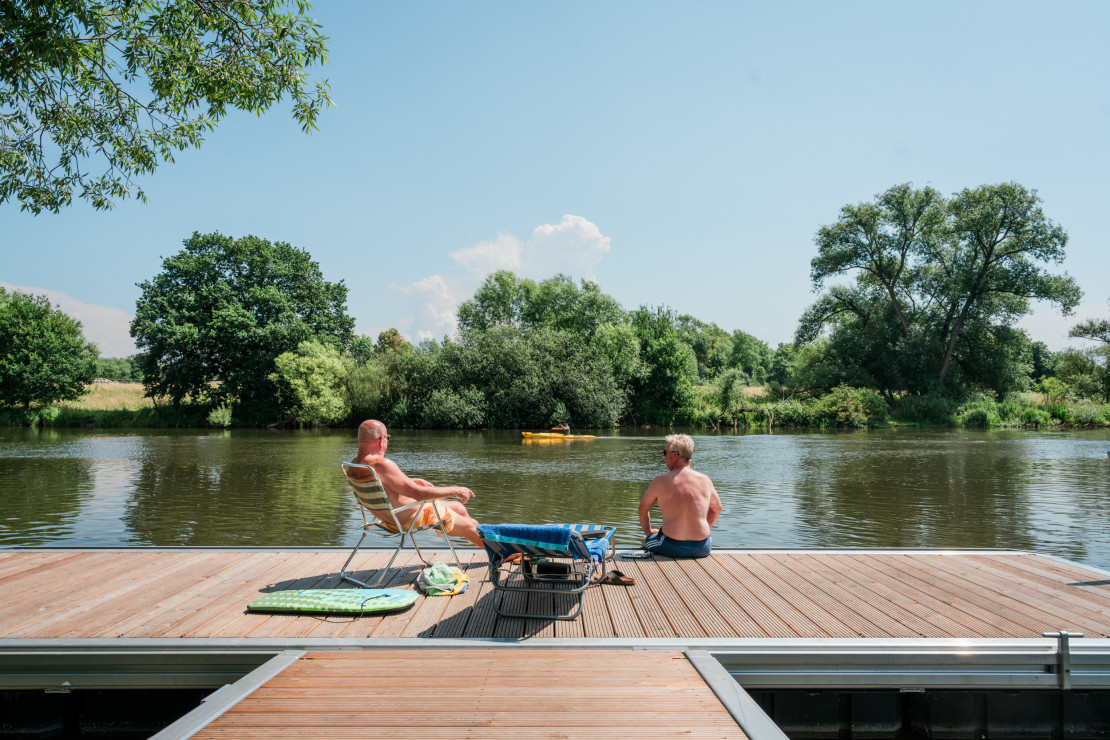 Two guests of the Kassel campsite enjoy a sunbath on the Fulda