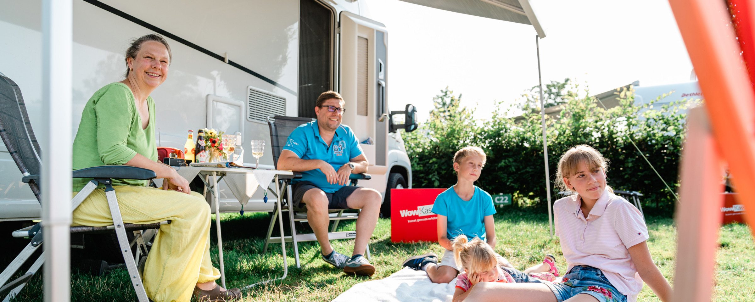 Family enjoying their stay at the Kassel campsite in front of their caravan