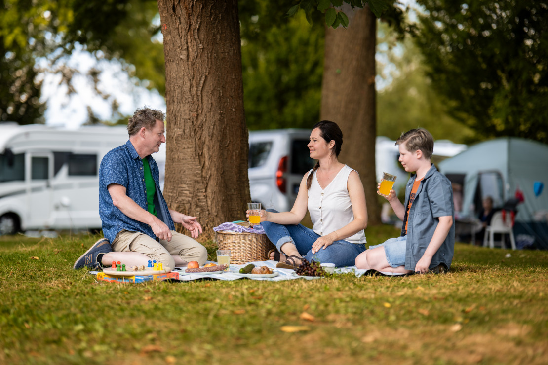 Drei Kinder sitzen am Fuldaufer des Campingplatz Kassel und genießen die Aussicht