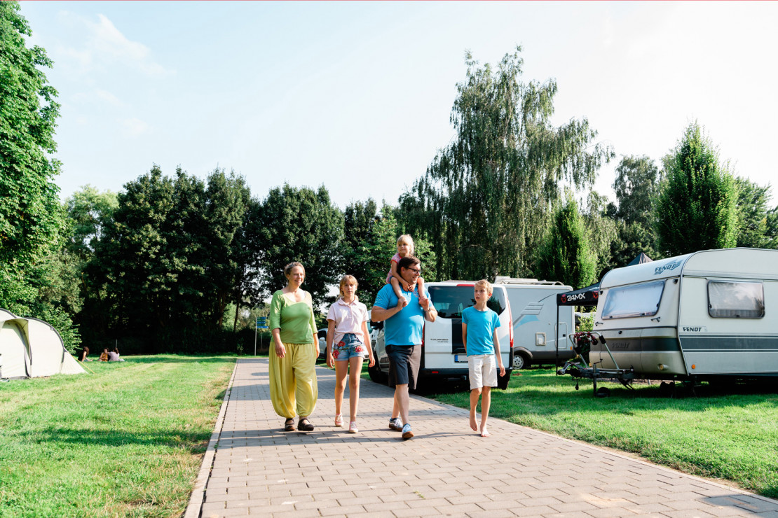 A family with three children strolls relaxedly across the campsite in Kassel